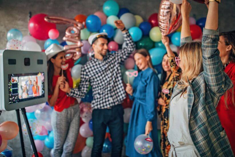 Joyful group with props and balloons captured by a photo booth at a lively party.