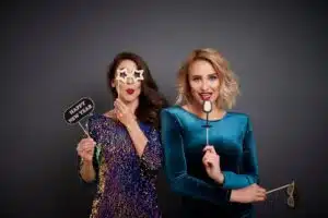 Two women holding props and smiling in a photo booth