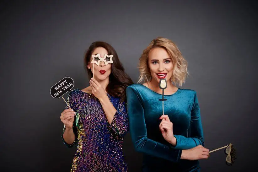 Two women holding props and smiling in a photo booth