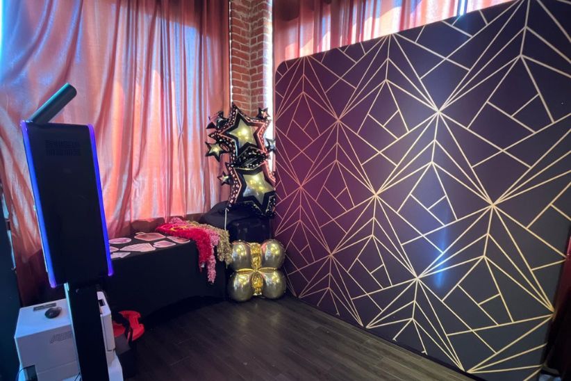 Photo booth setup with geometric backdrop and balloons.