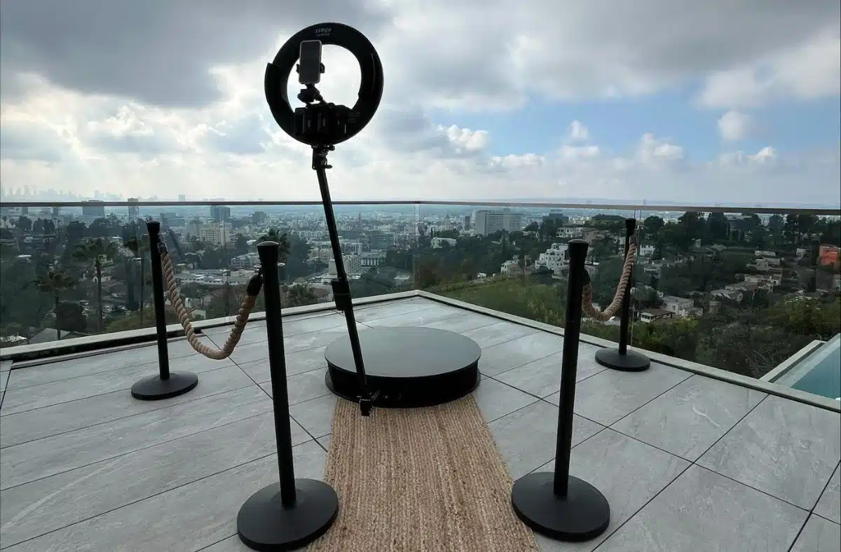 Outdoor 360 photo booth setup with stanchions and carpet, overlooking a city skyline.