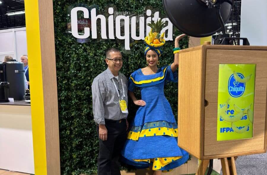 Man and woman in themed attire posing at a Chiquita photo booth with a green backdrop.