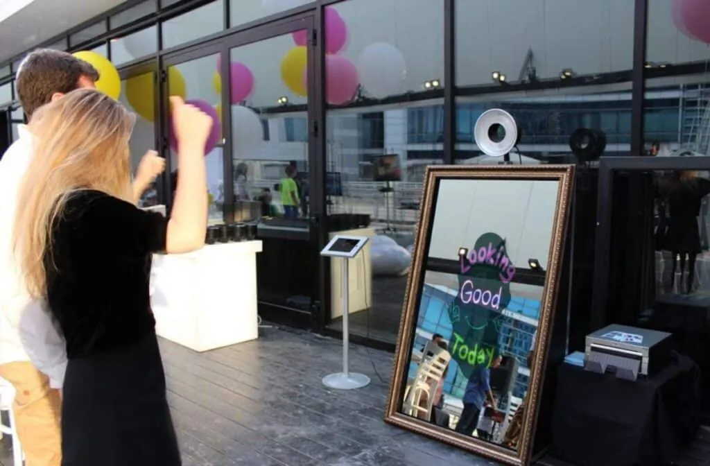 Guests using a mirror photo booth with 'Looking Good Today' message