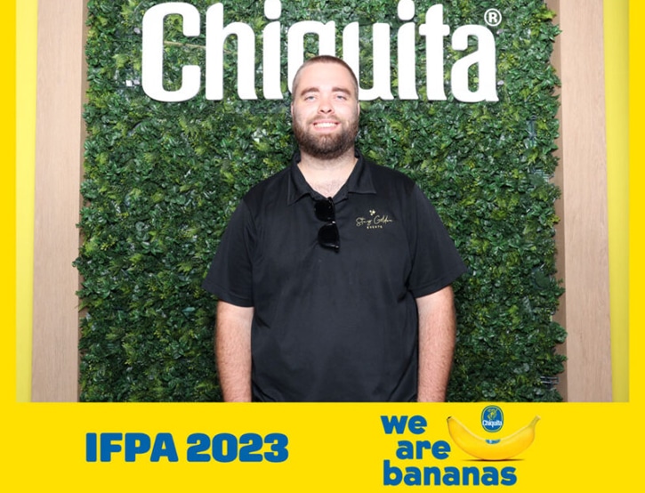 Man poses at Chiquita’s corporate photo booth with a green backdrop and "we are bananas" branding.