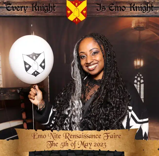Smiling woman holds a balloon at a themed corporate holiday party photo booth with a medieval backdrop.