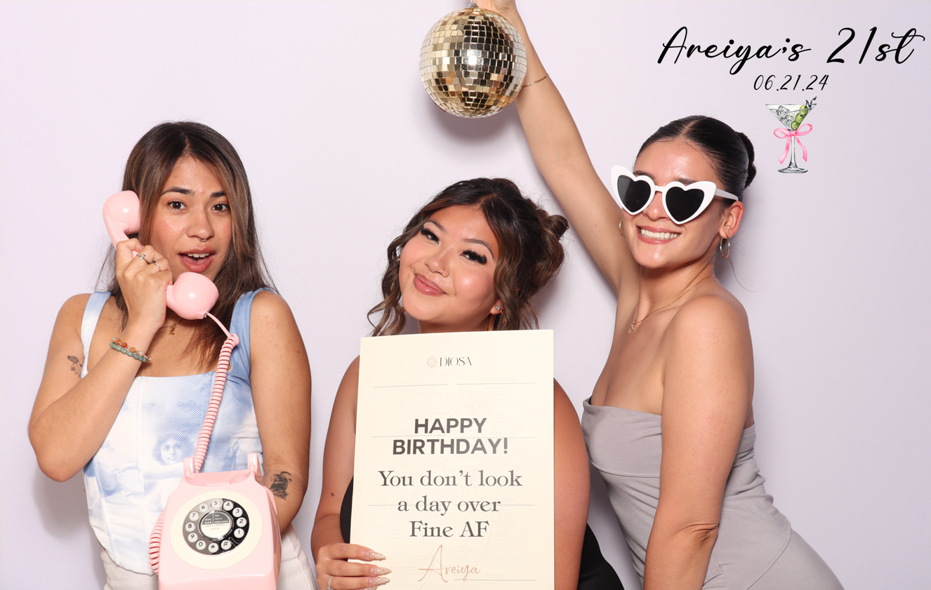 Three ladies posing in a photo booth for Areiya’s 21st birthday, with the celebrant in the middle.