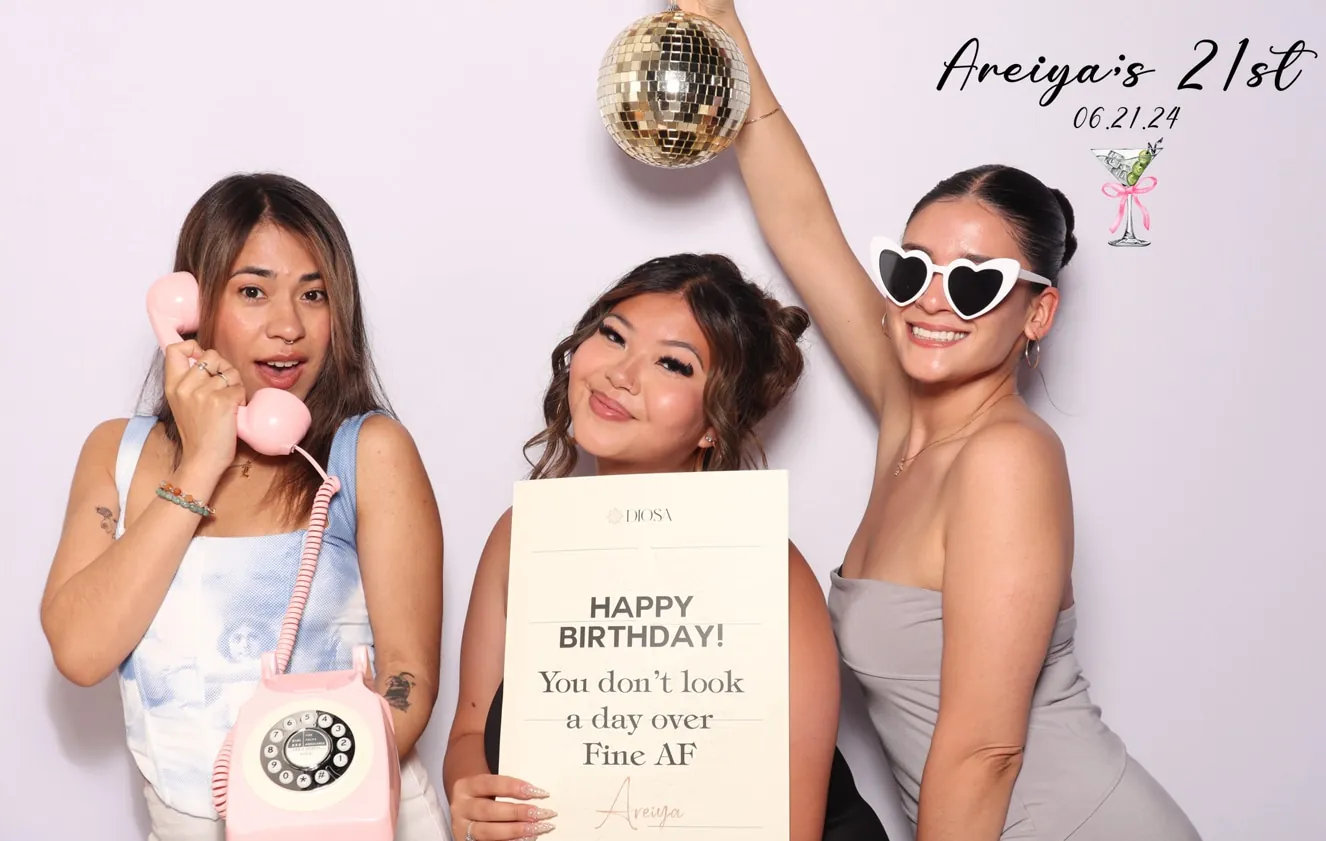 Three ladies posing in a photo booth for Areiya’s 21st birthday, with the celebrant in the middle.