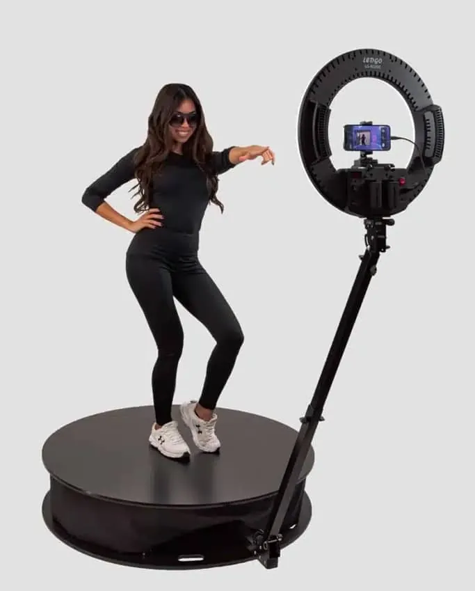 Woman posing on 360 photo booth platform with ring light and camera setup in Los Angeles event studio.