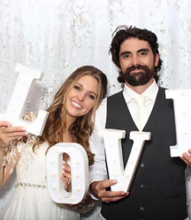 Happy couple in classic photo booth holding LOVE props, celebrating with smiles and sweet memories.