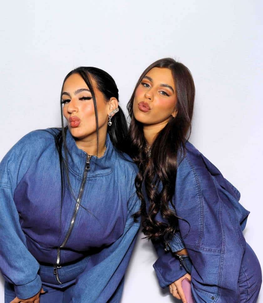 Two women in denim outfits posing playfully at the Spilled Denim photo booth in Anaheim.