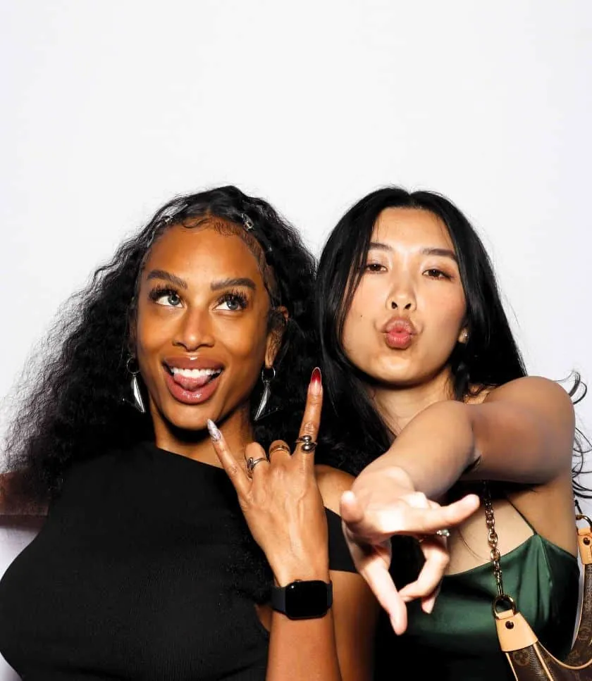 Two ladies posing at the Treyarch Black Ops photo booth in Beverly Hills, making playful hand signs.