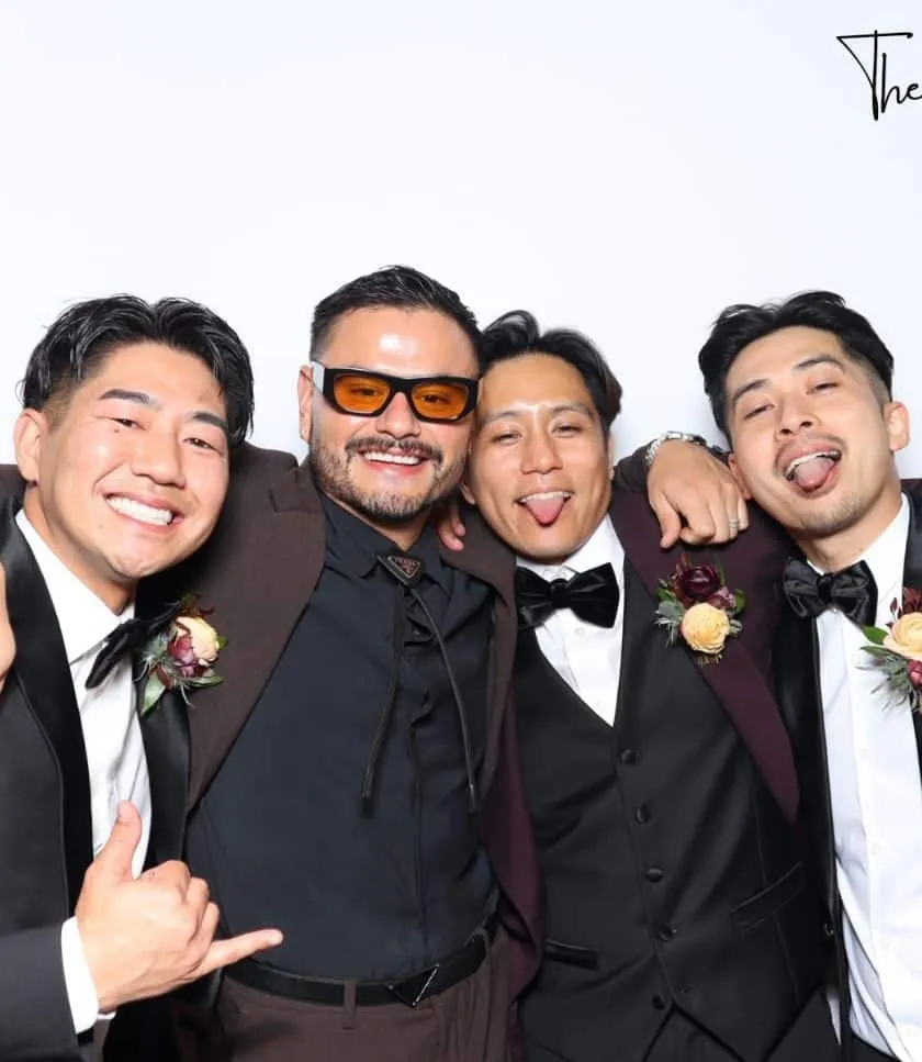 Four men in suits smiling and posing together at The Rico Wedding's photo booth rental in Burbank.