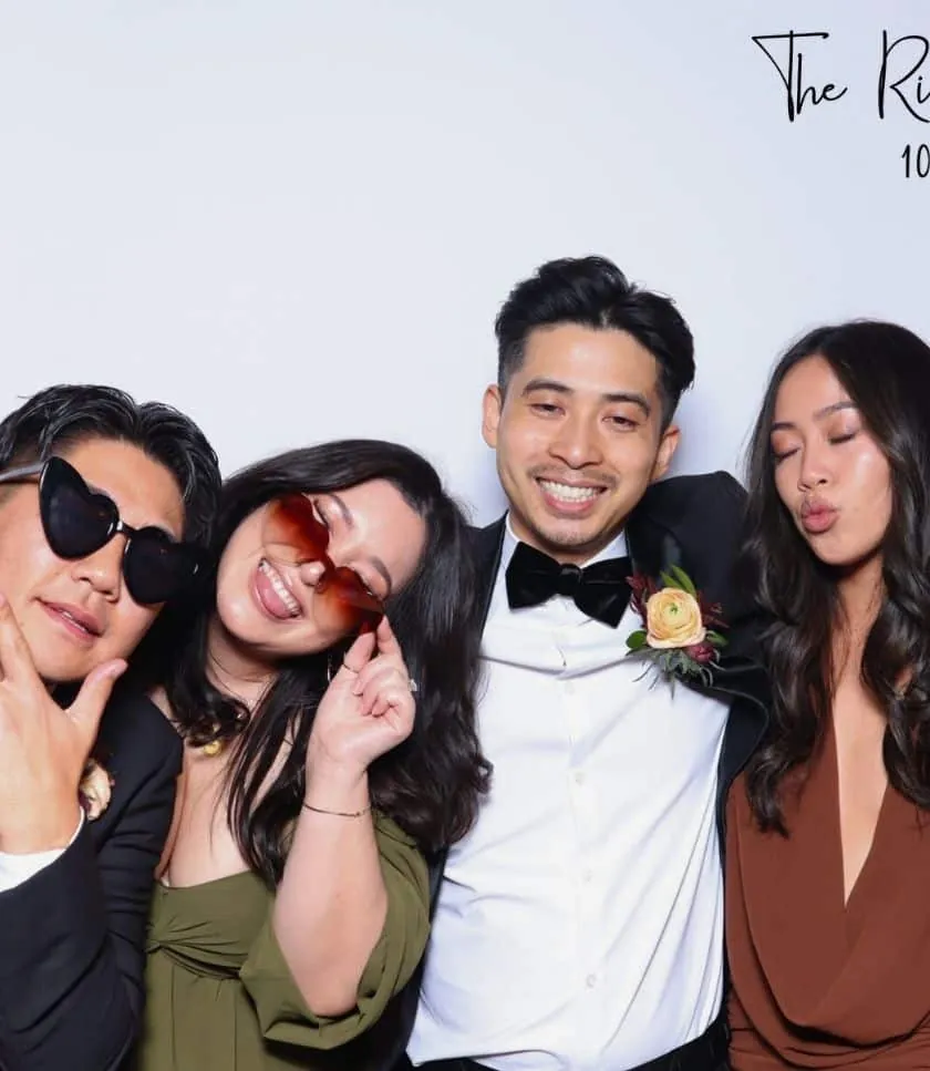 group of friends posing with props at The Rico wedding's photo booth in Carlsbad, smiling.