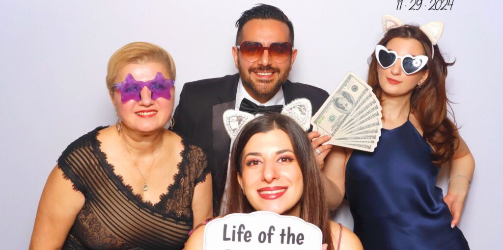A group posing with fun props at The Santander's event photo booth rental in Carlsbad, smiling and playful.