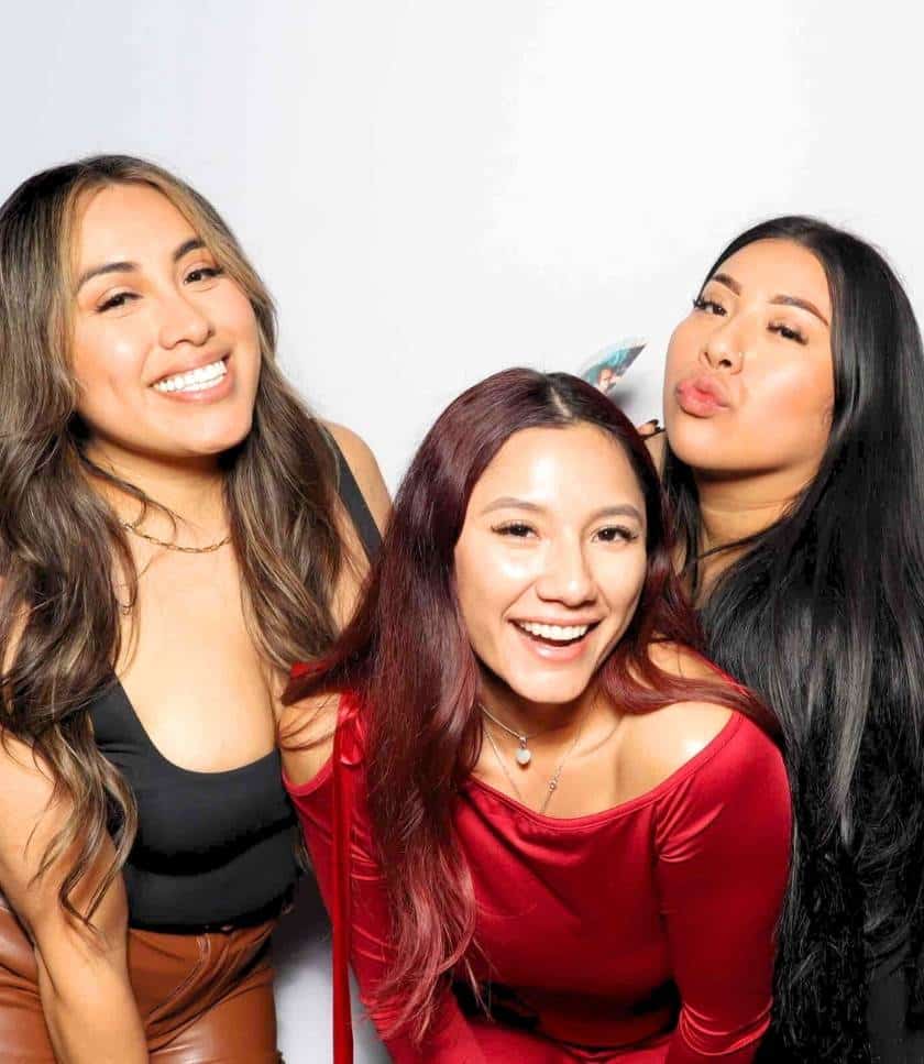 Ladies in stylish outfits smiling at Alexandroff Law Group photo booth in Chula Vista.