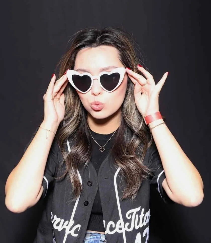 A woman posing with heart-shaped glasses at the Service Titan photo booth rental in Irvine, puckering lips.