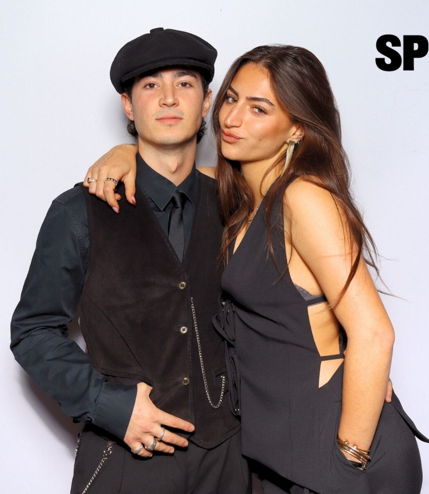A stylish couple posing at the Spilled Denim photo booth in Newport Beach, dressed in chic black outfits.