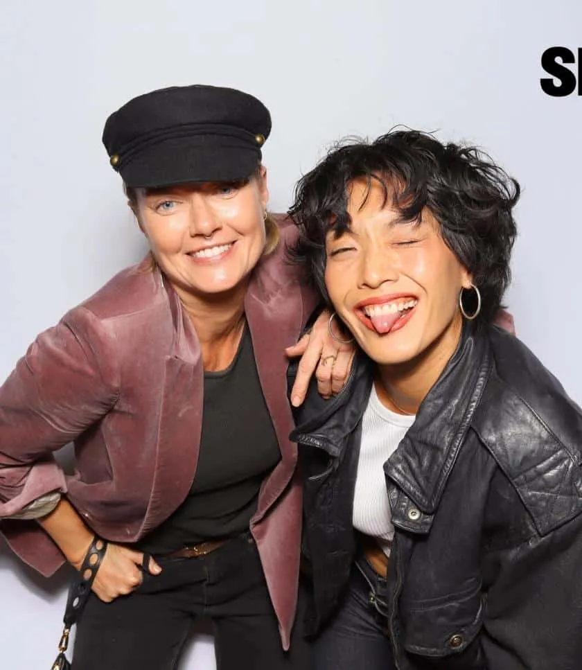 Two friends posing playfully at the Spilled Denim photo booth in Oceanside, smiling and making silly faces.