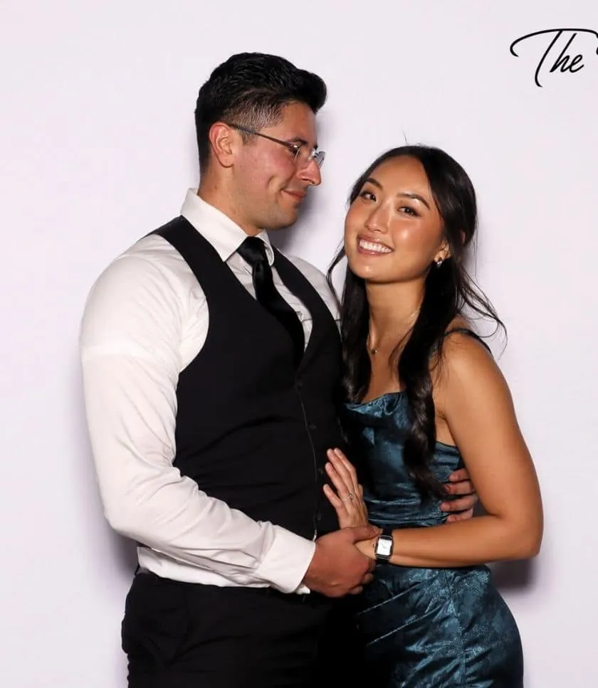 A smiling couple posing at The Watkins' wedding photo booth in Redondo Beach, dressed in formal attire.