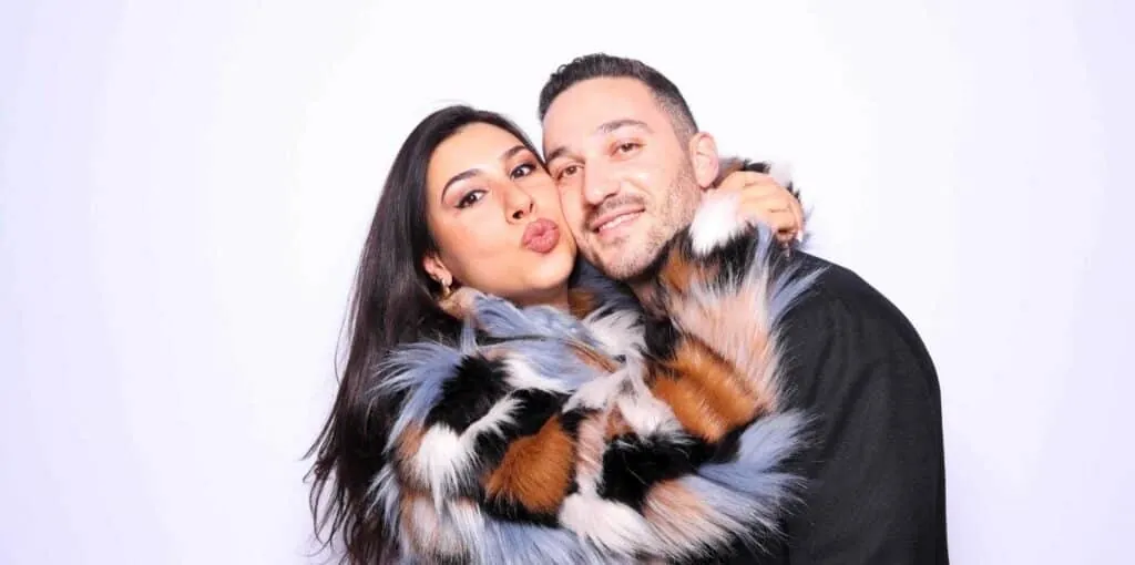 Stylish couple hugging and posing at Sasooness Law Group Holiday party in a photo booth rental in Riverside.