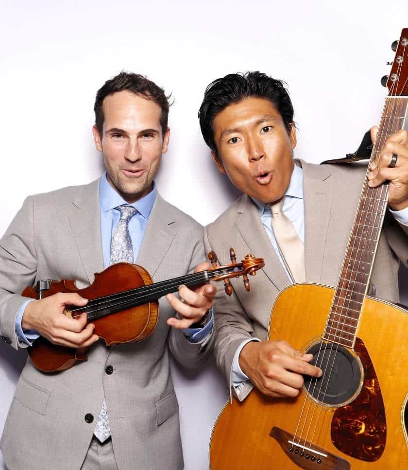 Men in suits posing with violin and guitar props at photo booth rental in San Diego - Curate's event.