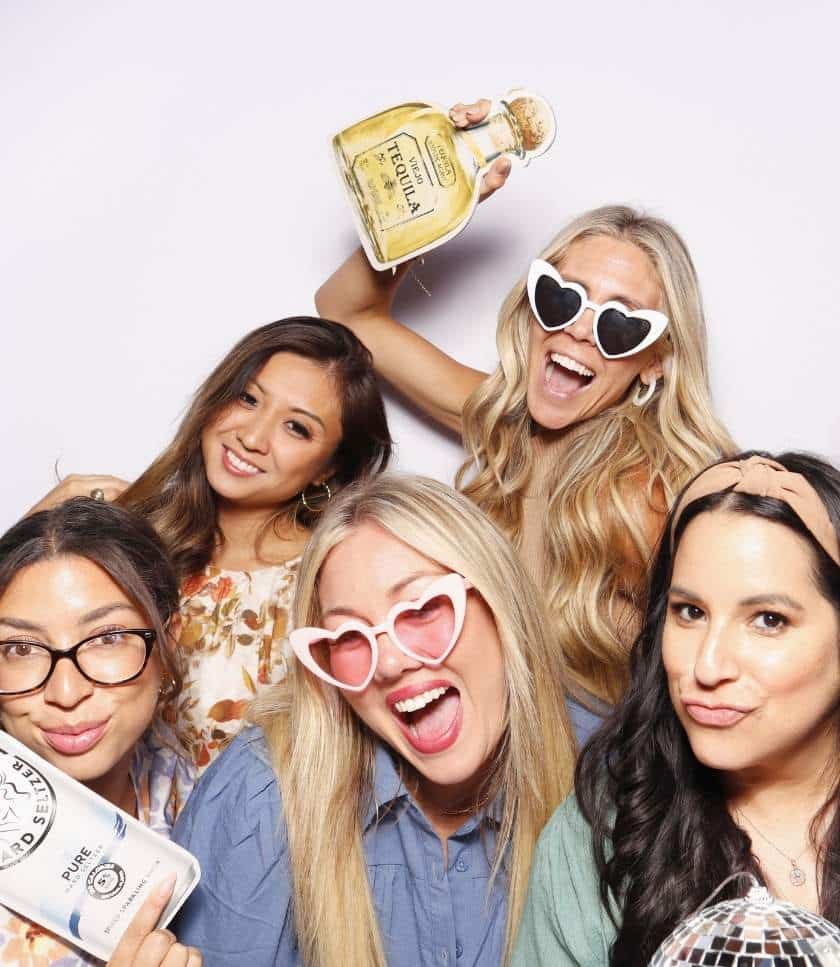 Smiling ladies pose with fun props at an event with a photo booth rental in Hollywood.