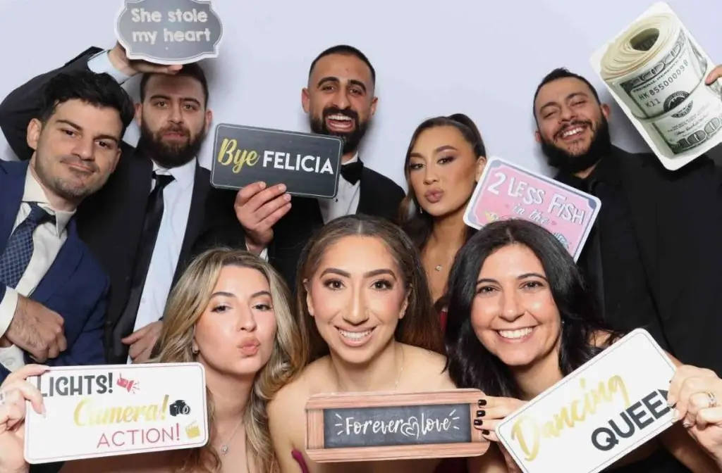 a group of people posing with handheld witty signs for a photo in a photo booth