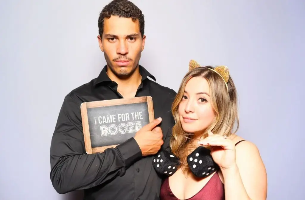 A couple posing for a photo booth with a large plush dice