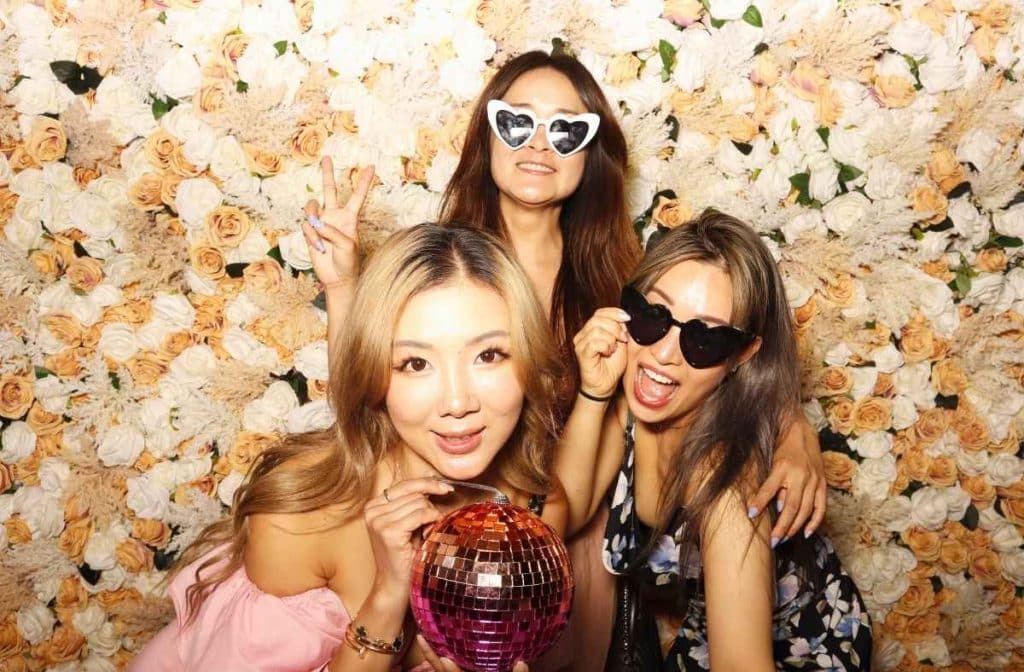 three ladies posing for the camera in a photo booth with a disco ball