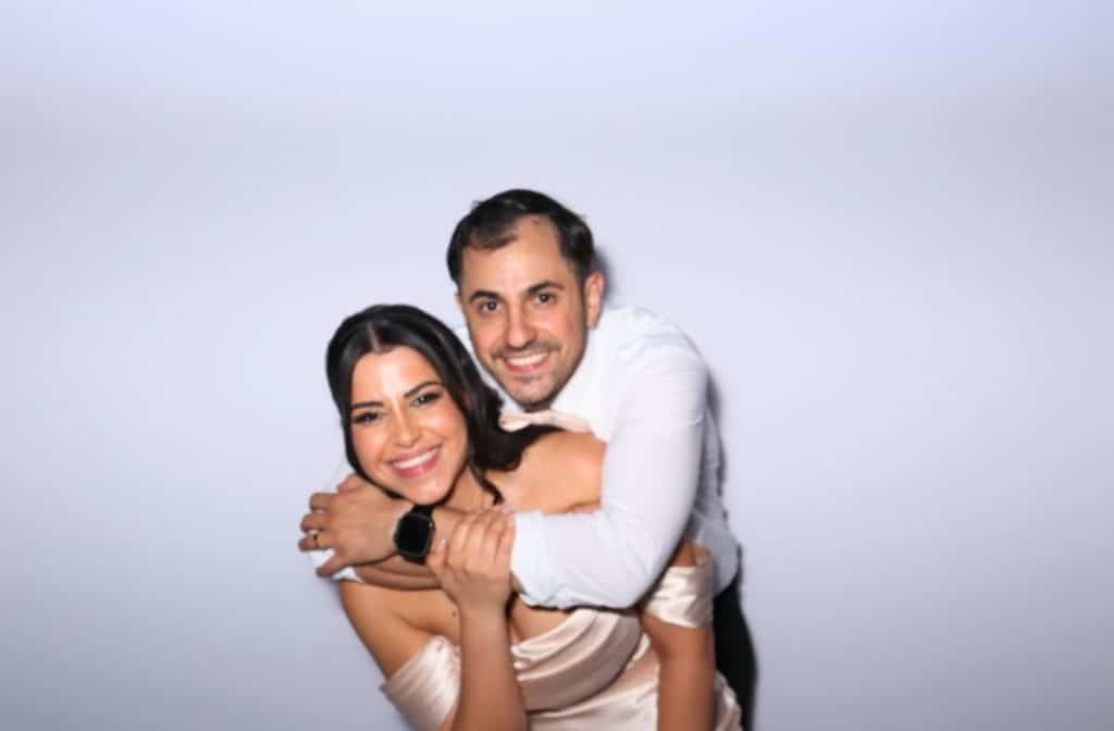 A married couple posing for a photo booth at their wedding