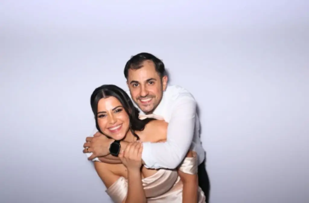 A married couple posing for a photo booth at their wedding
