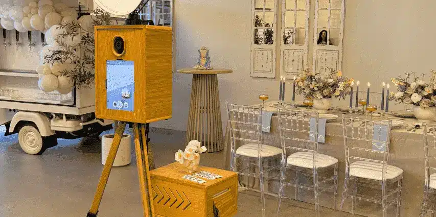 A Glam Photo Booth beside elegant wedding table with flowers and candles.