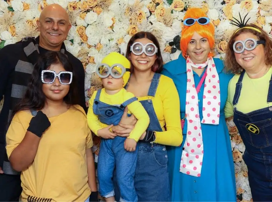 Family dressed as Minions and Gru posing together with goggles and colorful outfits in a photo booth.