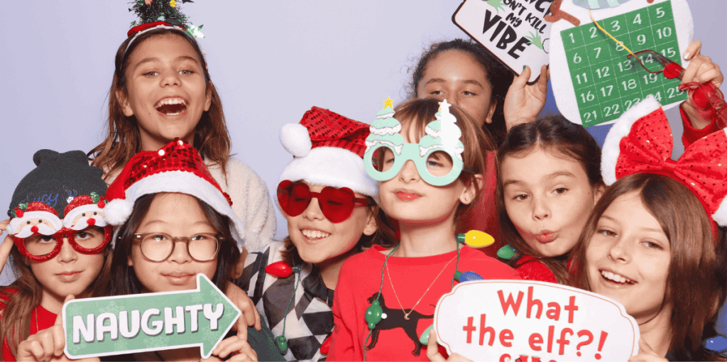 a group of children posing for a photo booth with christmas props