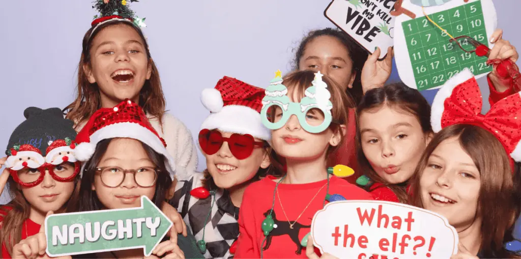 a group of children posing for a photo booth with christmas props