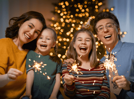a family holding sparklers in front of a christmas tree
