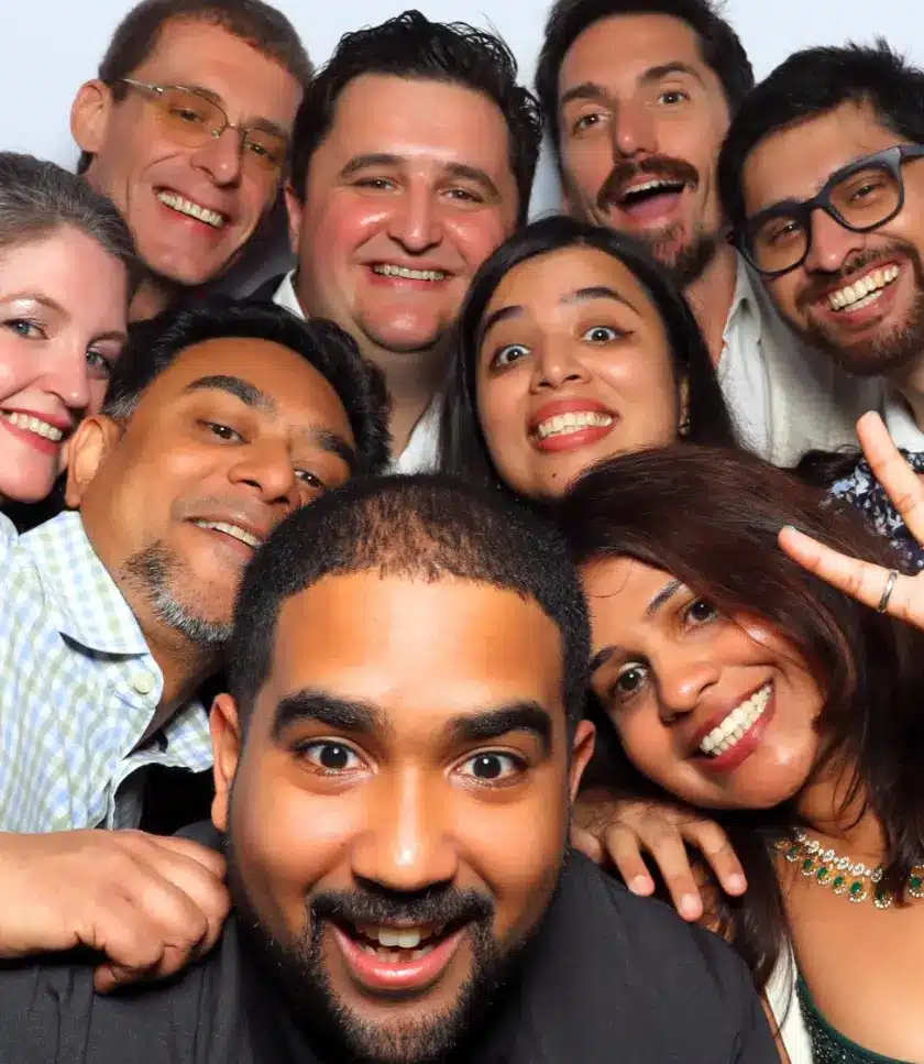 A group of friends smiling and posing for a gender reveal photo booth.