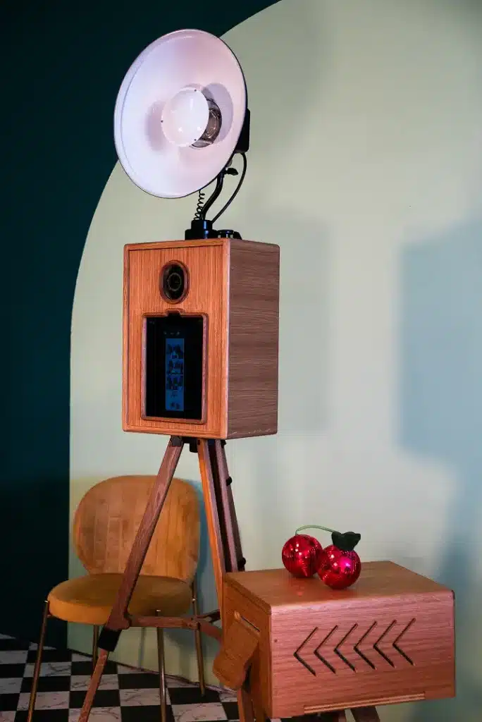 A glam photo booth rental with studio light, tripod stand, wooden finish, and matching printer shell in a vintage setup.