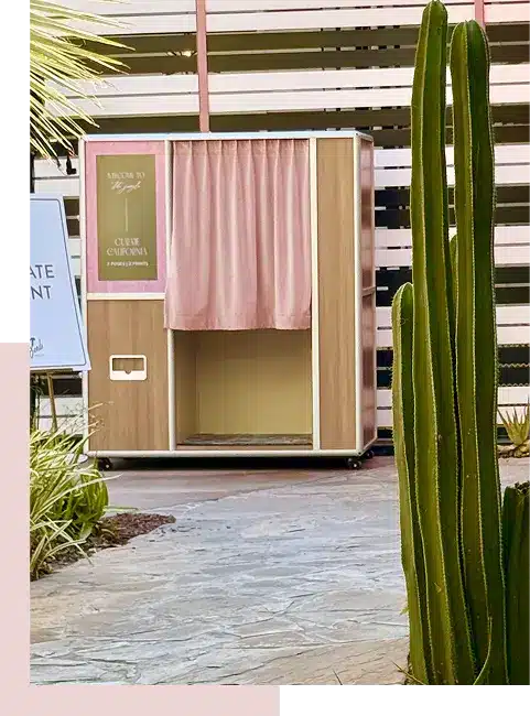 Custom enclosed photo booth with pink curtain and wood panels set up for an outdoor event in Los Angeles.
