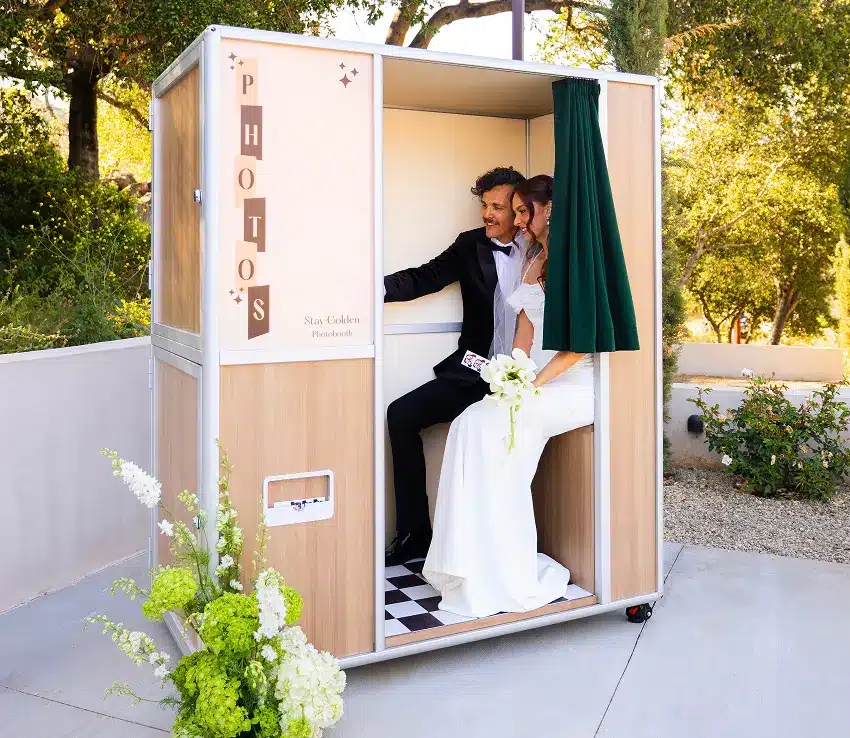 A newlywed couple posing inside a photo booth rental during a wedding at a Los Angeles venue.
