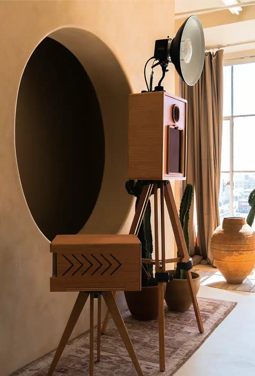 A glam photo booth in a studio set up beside a matching print station in a warm indoor event space.