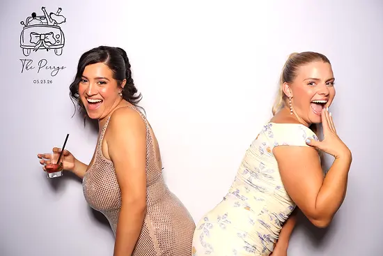 Two women stand back-to-back, laughing