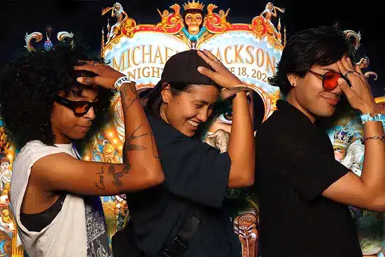 Three friends place hands on their heads and strike a synchronized dance pose