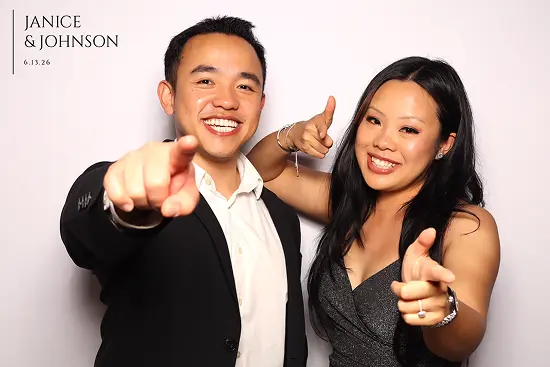 Smiling couple points at the camera with playful finger-gun gestures