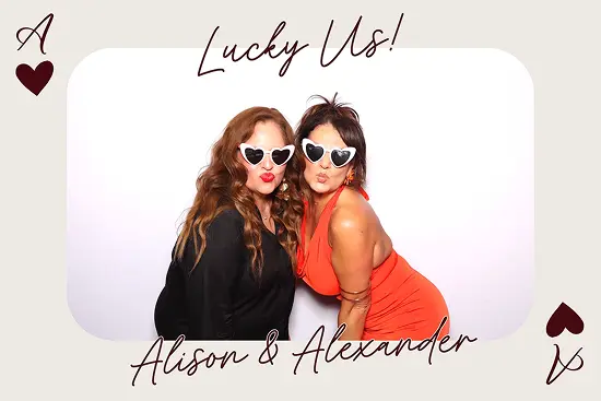Two women wear heart-shaped sunglasses and make kissy faces