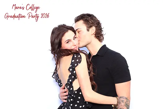 Man kisses a woman on the cheek as they embrace in a sweet couples photo booth pose.