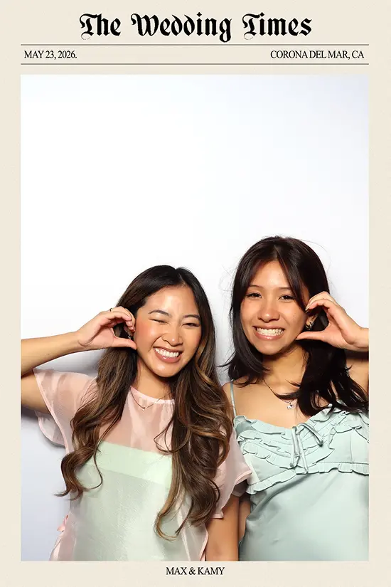 Two women smile and form heart shapes with their hands