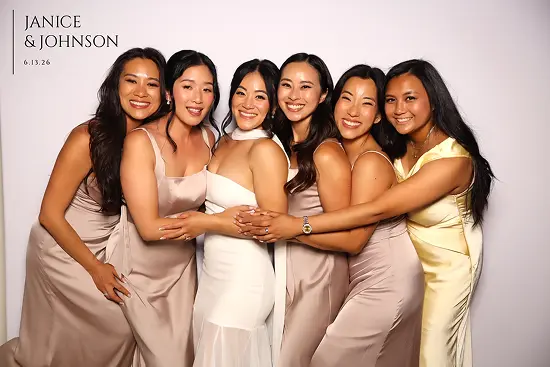 Six women stand close together with arms around each other