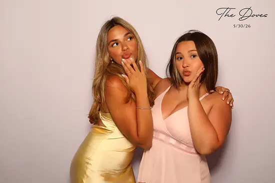 Two women make kissy faces with hands on their cheeks