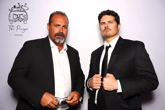 Two men in black suits strike serious, confident poses together